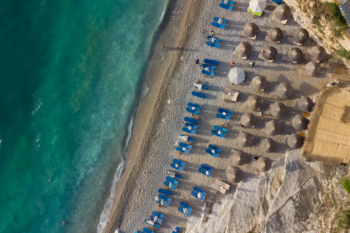 Praia com espreguiçadeiras e mar turquesa em ilha grega