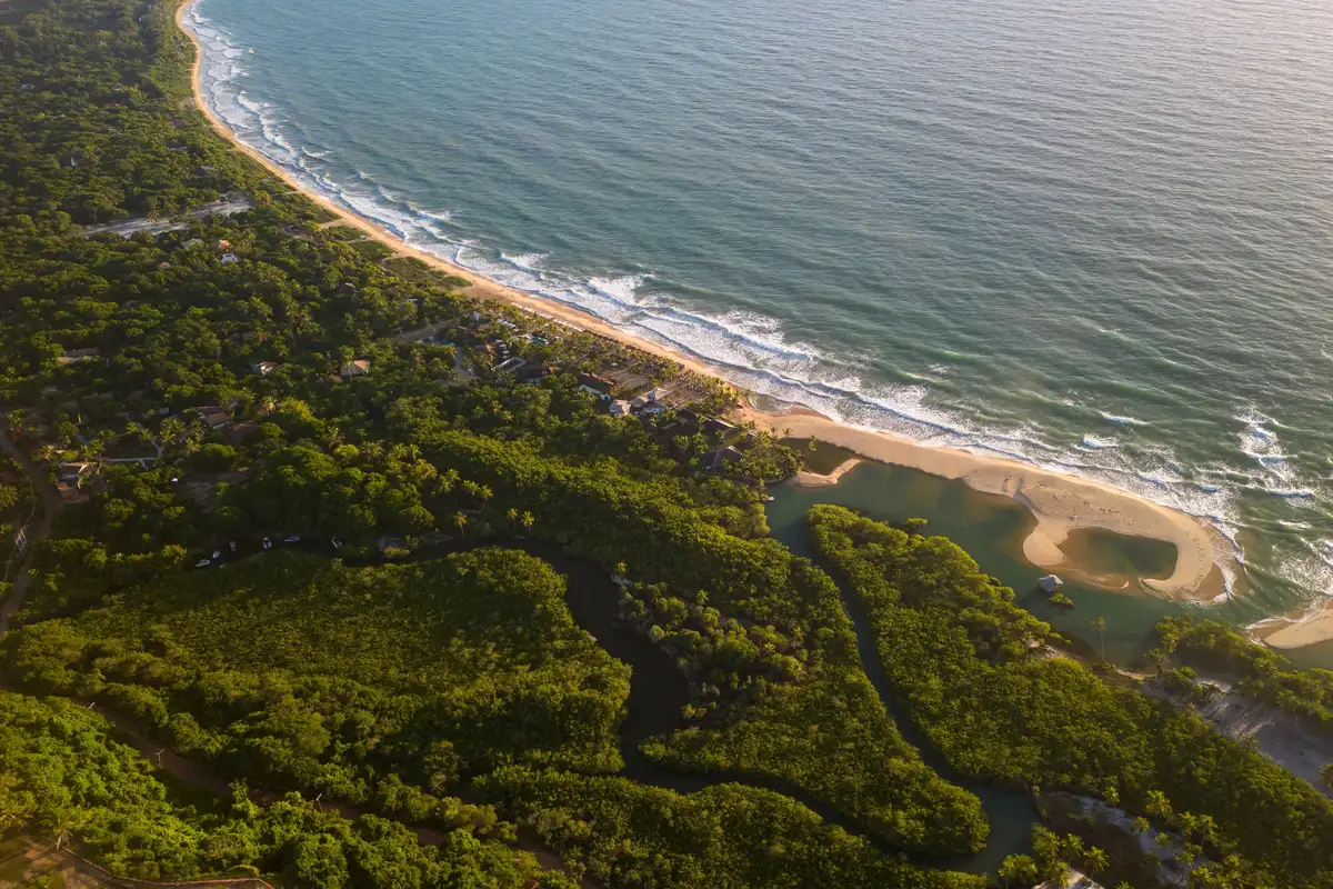 Vista aérea de Trancoso, Bahia, com a praia e pousadas — cenário do réveillon 2027