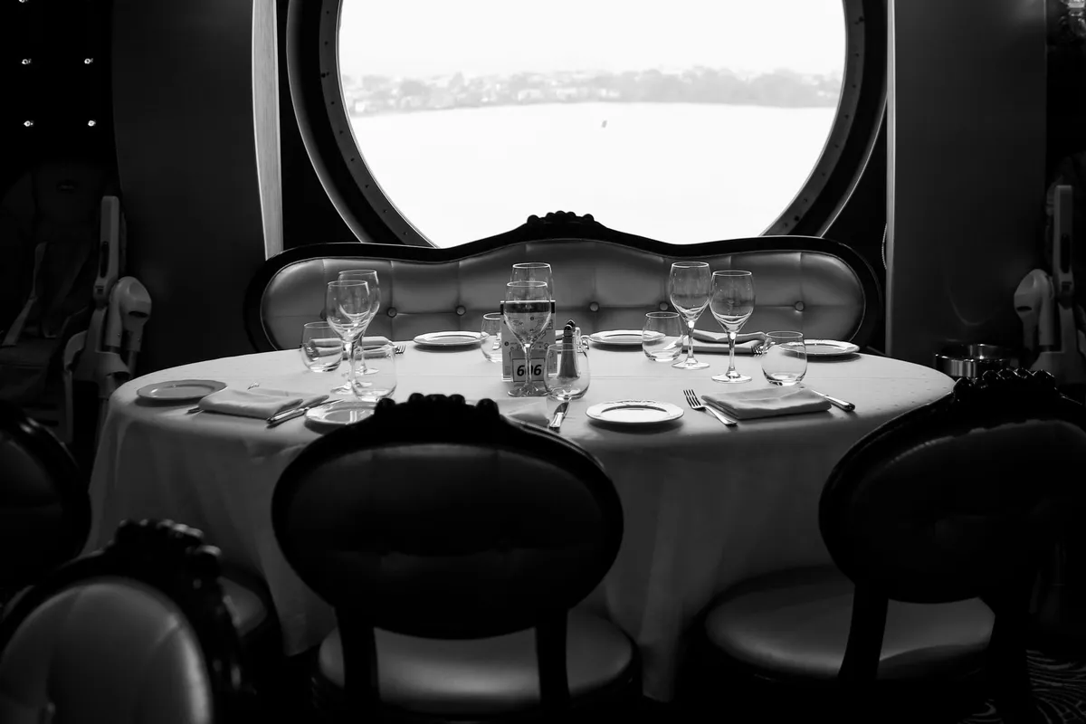 Mesa posta com vista para o mar pela janela redonda de restaurante de navio de cruzeiro