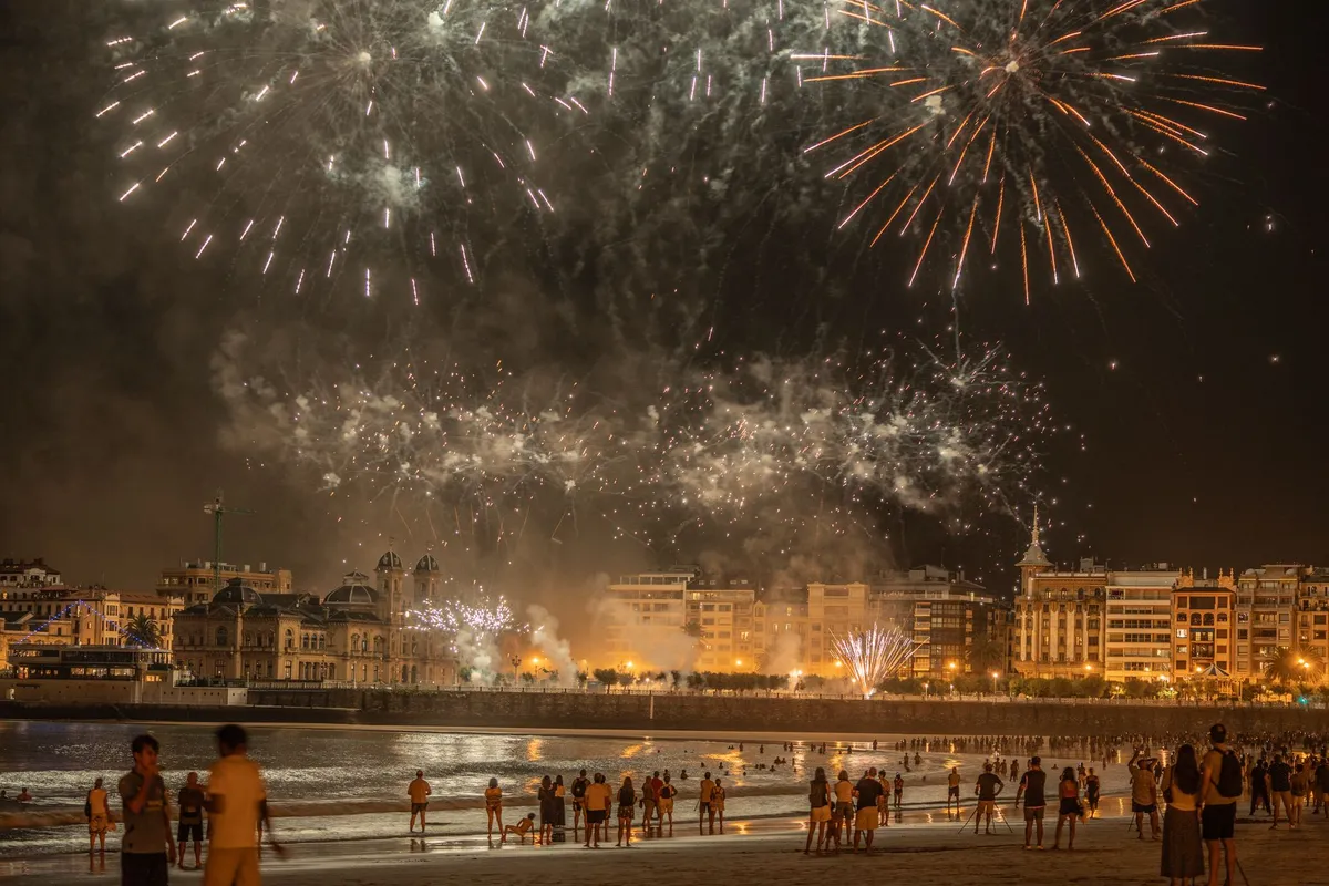 Pessoas assistem a fogos de artifício em uma praia durante uma celebração noturna