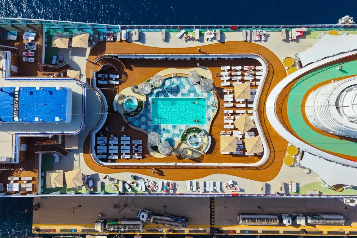 Área de piscina no deck superior de navio de cruzeiro com famílias em dia de sol