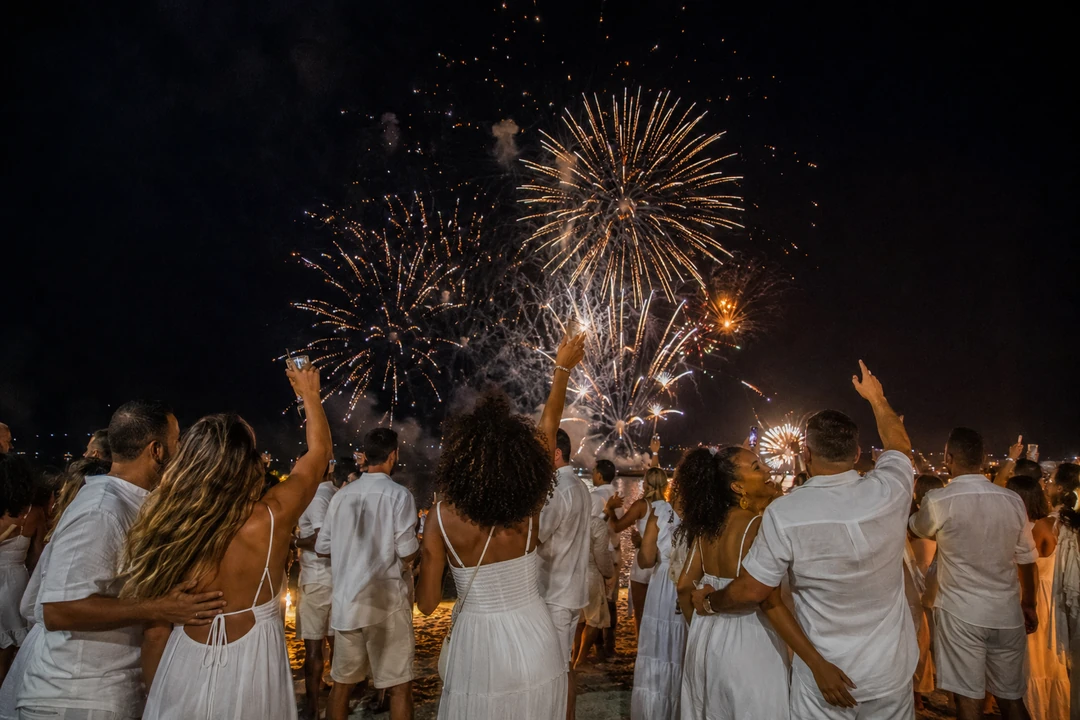 Pessoas de branco celebram o Réveillon sob fogos à meia-noite
