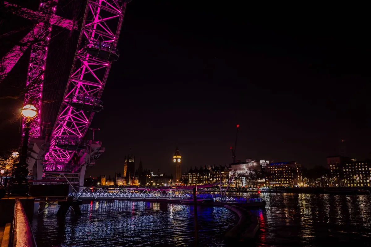 London Eye e Big Ben iluminados à noite às margens do Tâmisa em Londres