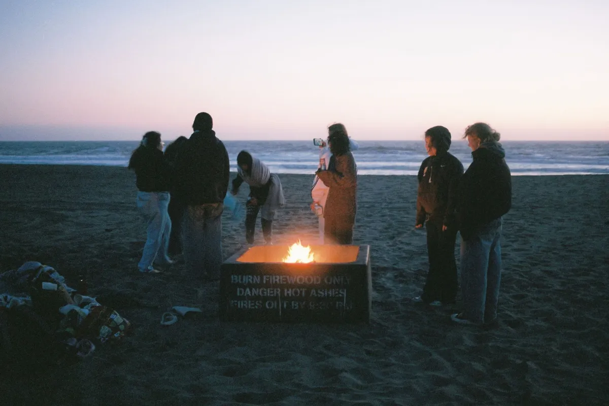 Grupo reunido na praia à noite, clima de festa de réveillon