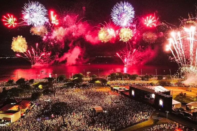Fogos de artifício coloridos sobre o Guaíba e o público no Parque Harmonia na virada de ano em Porto Alegre