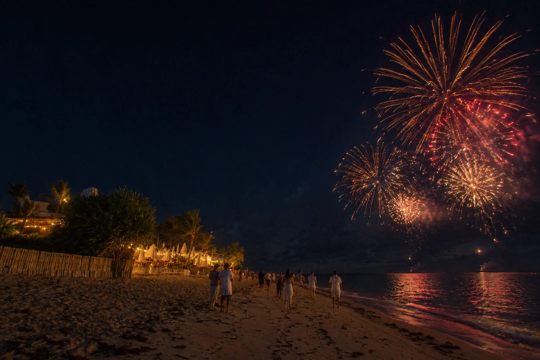 Pessoas vestidas de branco observam fogos sobre uma praia à noite