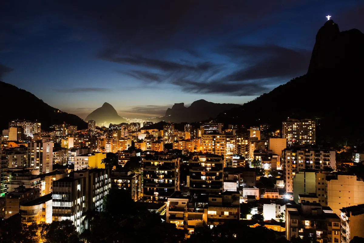 Vista aérea do Rio de Janeiro à noite com iluminação da cidade e o Corcovado ao fundo