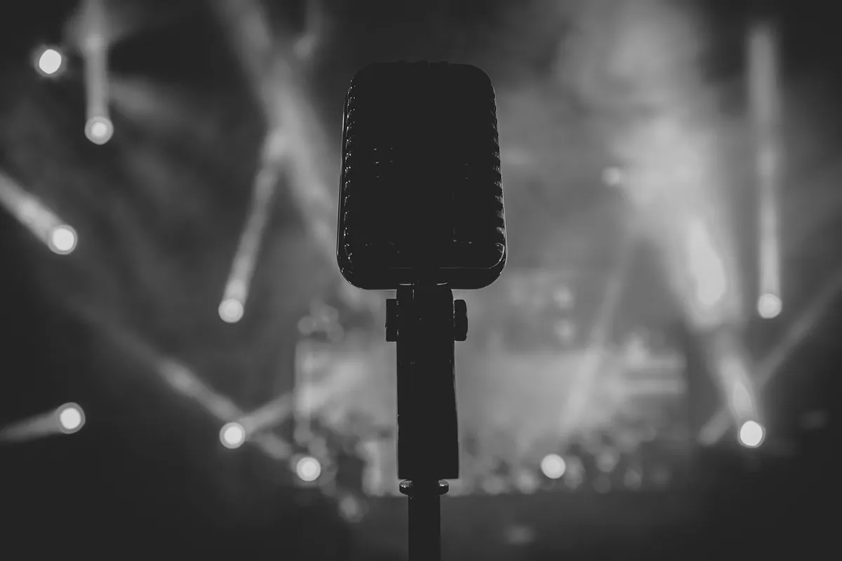 Microfone no palco com luzes de show, imagem ilustrativa