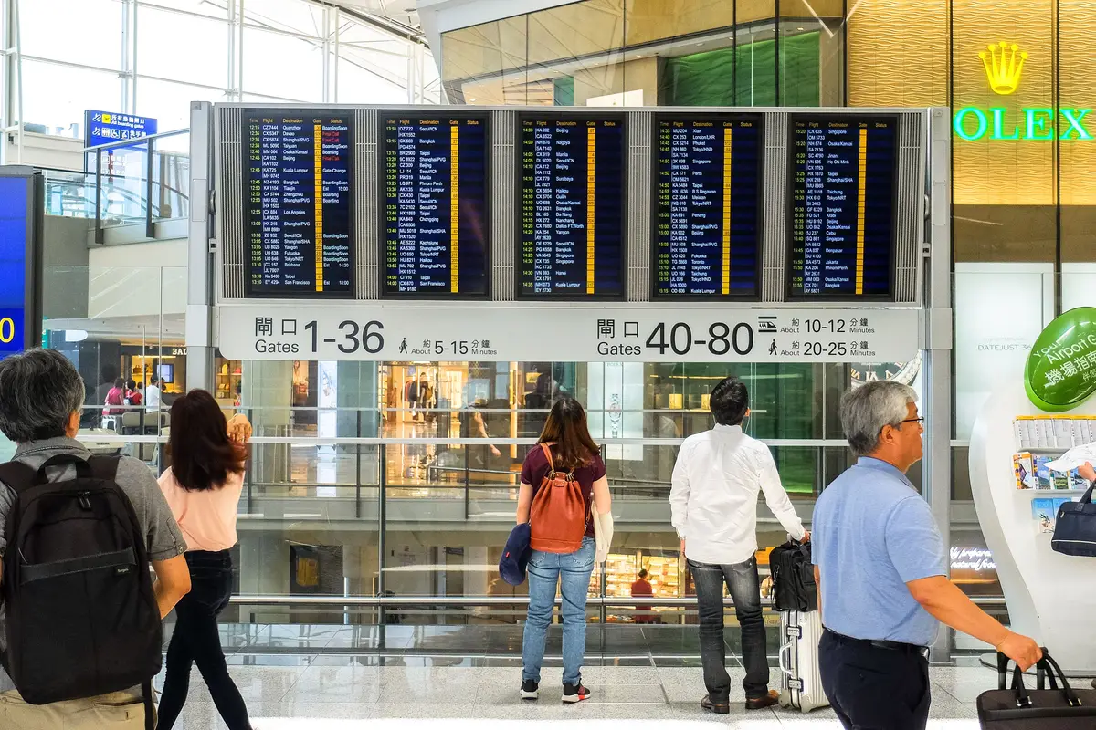 Passageiros diante do painel de partidas em aeroporto