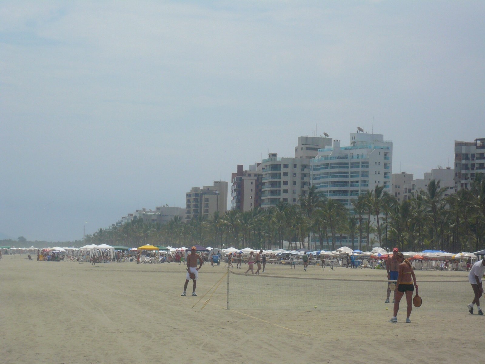 Praia de São Lourenço com edifícios residenciais e coqueiros na orla.