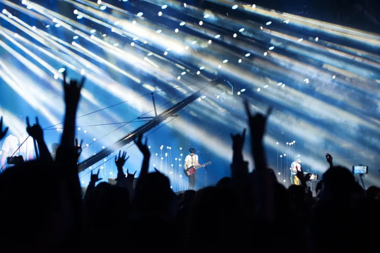 Público diante de palco iluminado em show de rock