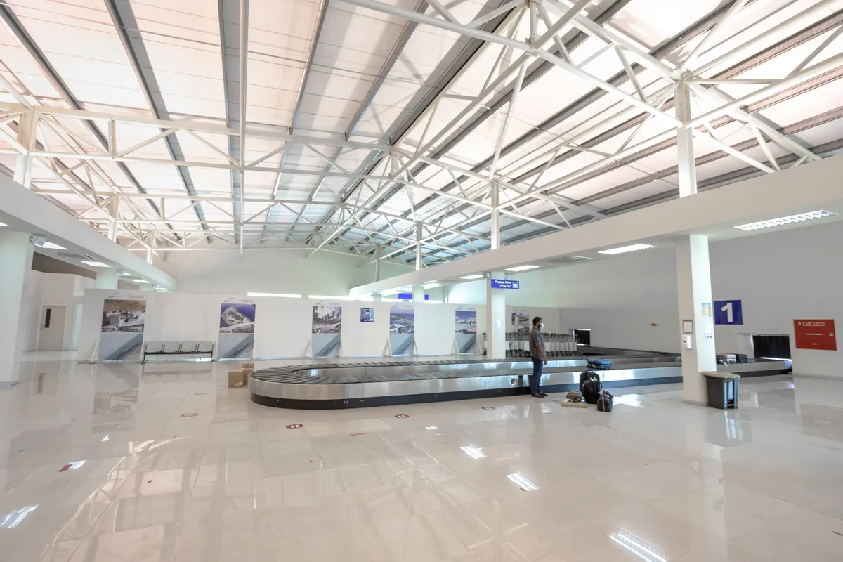 Passageiro aguardando junto à esteira de bagagens em um aeroporto