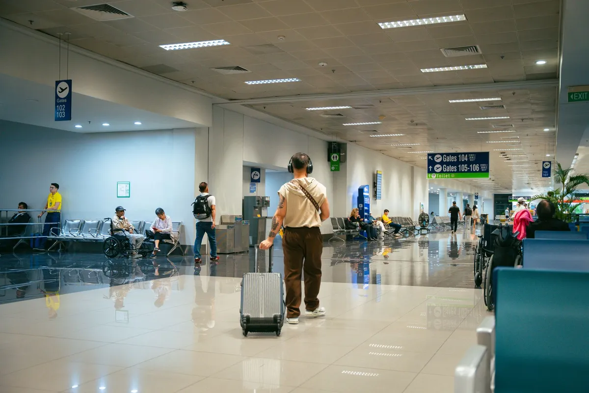 Passageiros circulam por terminal de aeroporto com uma pessoa usando cadeira de rodas