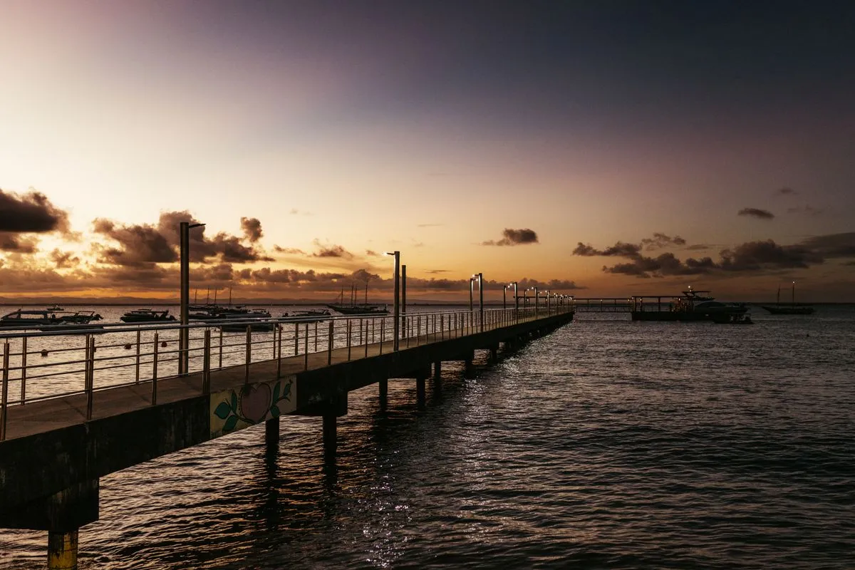 Píer de Barra Grande ao pôr do sol, com barcos, na Península de Maraú (BA)