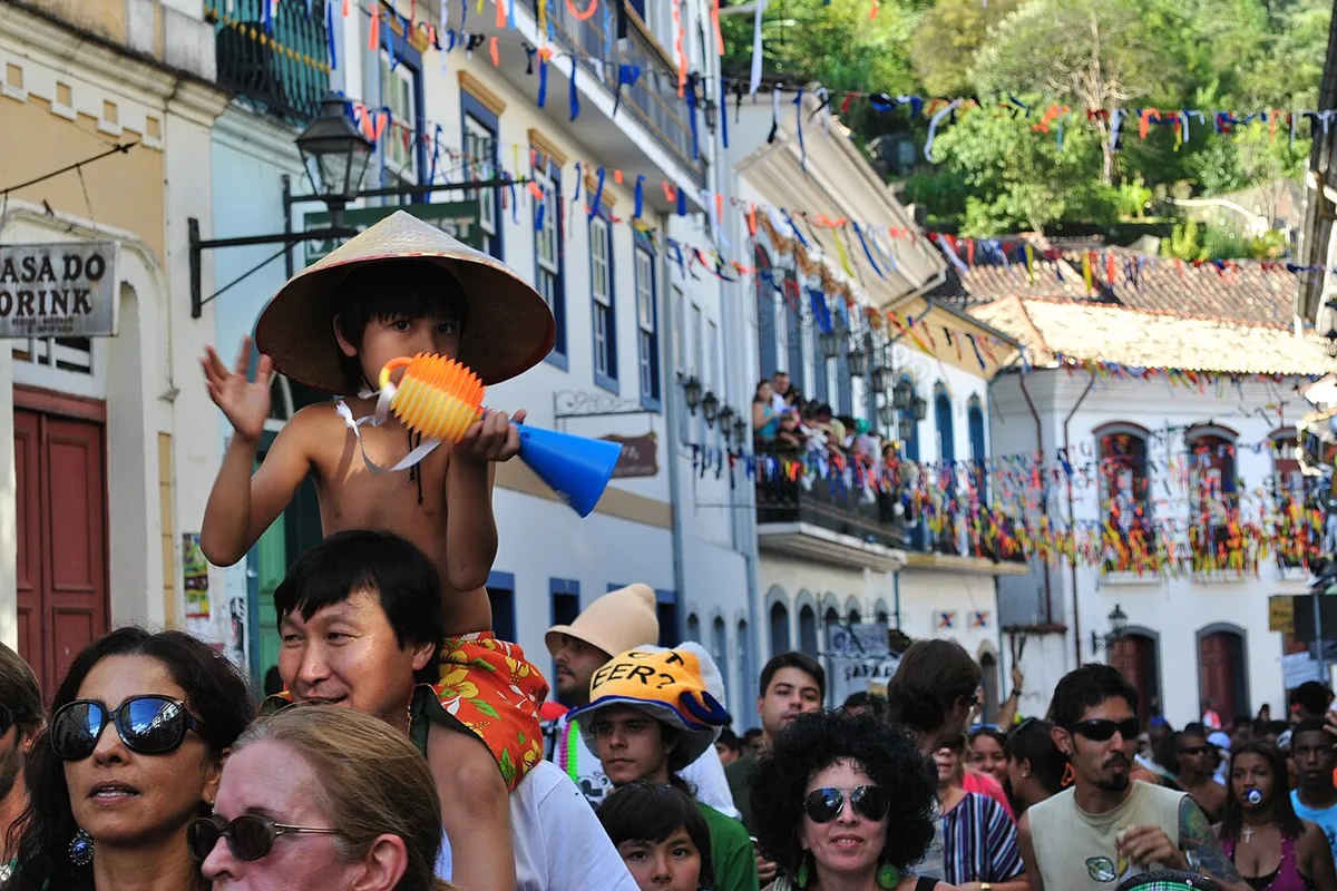 Foliões em rua enfeitada com bandeirinhas no Carnaval de Ouro Preto