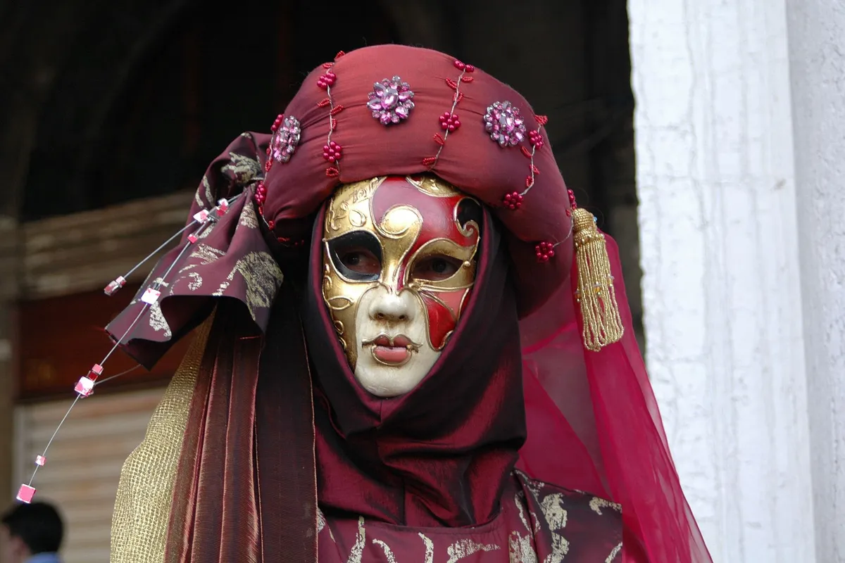 Pessoa com máscara veneziana e traje tradicional de Carnaval