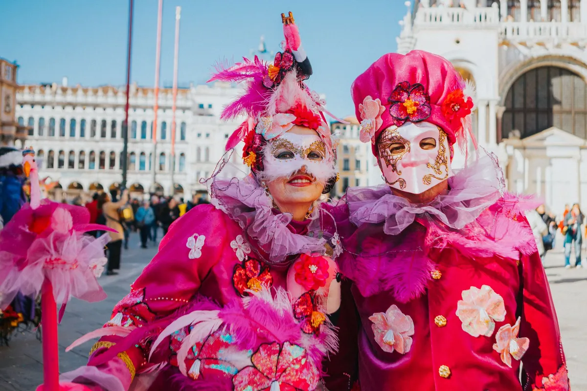 Foliões com fantasias e máscaras venezianas na Praça de São Marcos durante o Carnaval de Veneza
