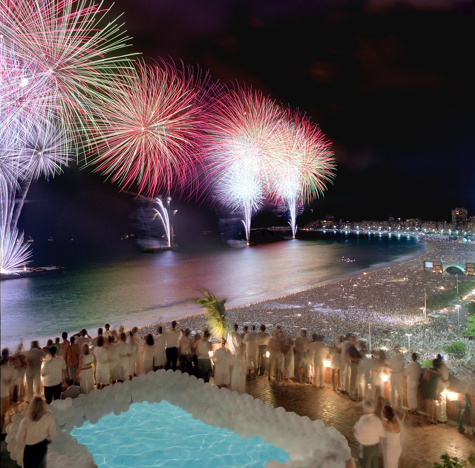 Fogos de artifício sobre a Praia de Copacabana, com a curva da orla e a multidão na virada de 2004, Rio de Janeiro