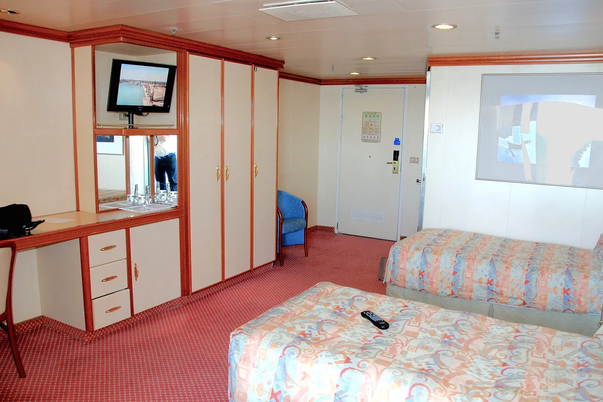 Cabine acessível de navio de cruzeiro com camas baixas, piso livre e porta larga