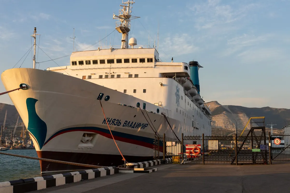 Navio de passageiros atracado no cais ao fim da tarde, com a passarela do terminal