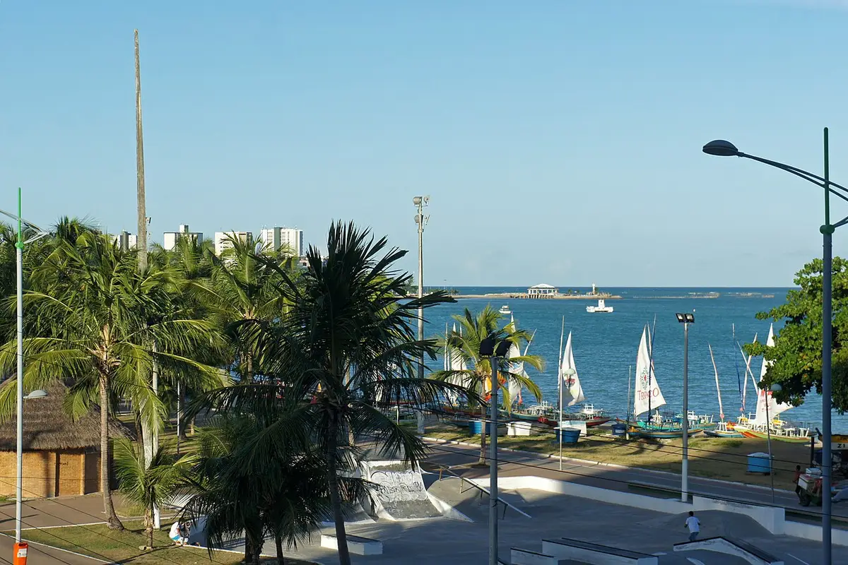 Orla da Pajuçara, em Maceió, com coqueiros, jangadas e mar azul