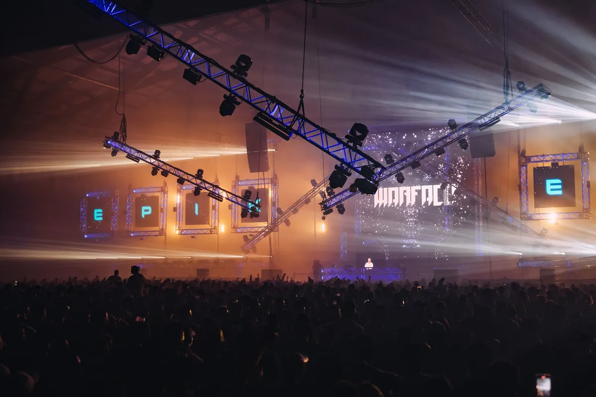 Palco de festival de música eletrônica iluminado à noite com público