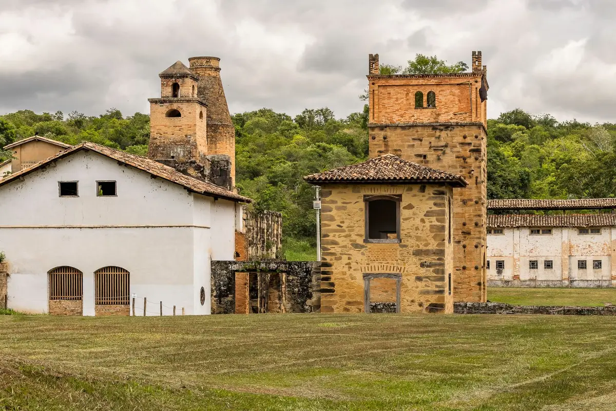 Edificações rurais entre jardins e árvores, em imagem de contexto para o comparativo