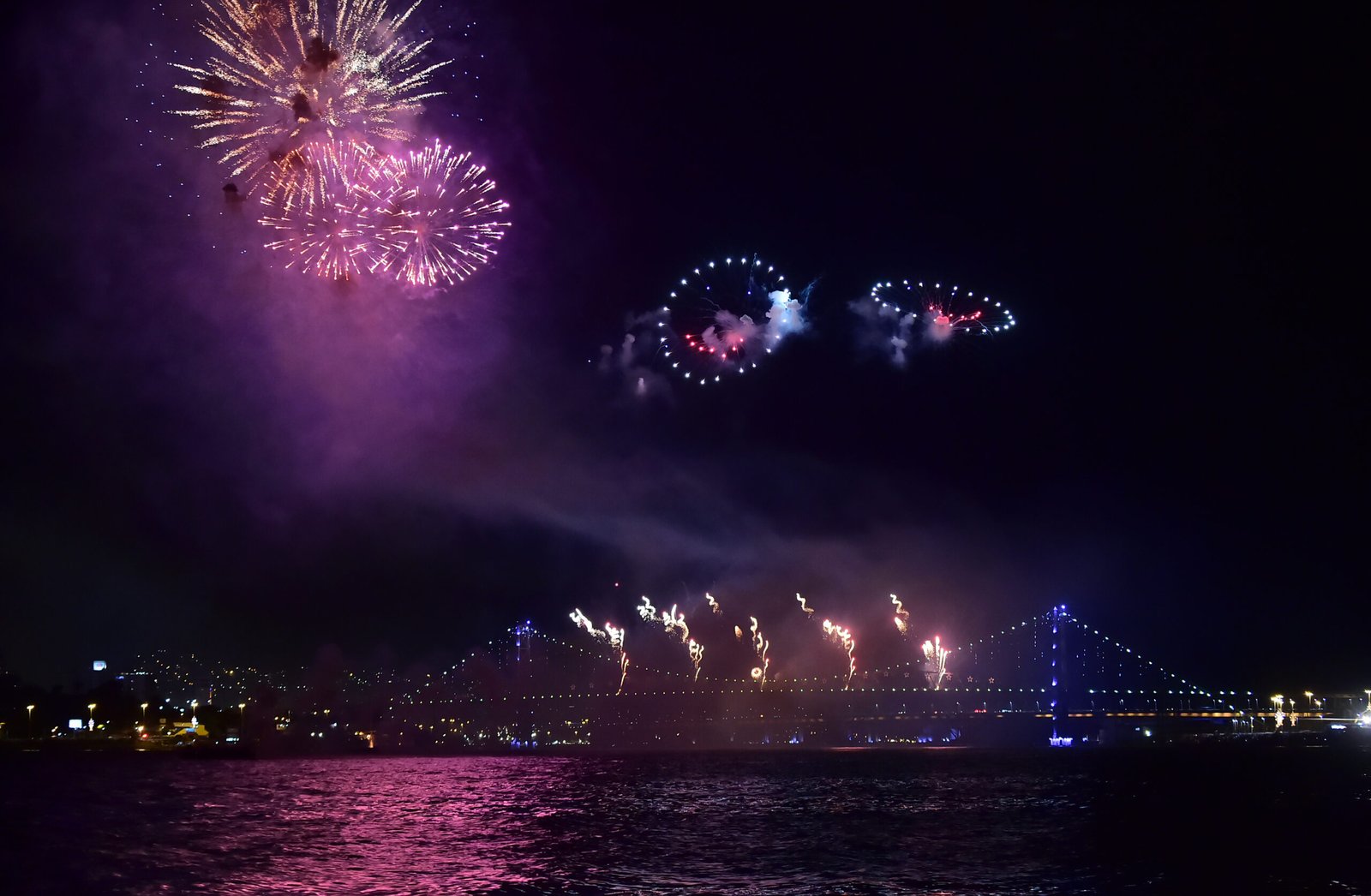 Fogos coloridos sobre a Ponte Hercílio Luz e a baía de Florianópolis na virada