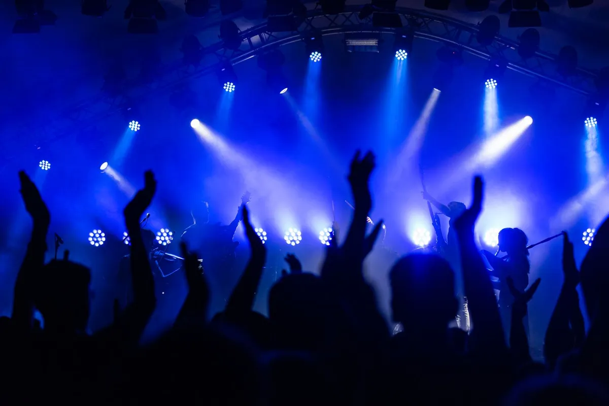 Banda tocando em palco com luzes coloridas, foto ilustrativa