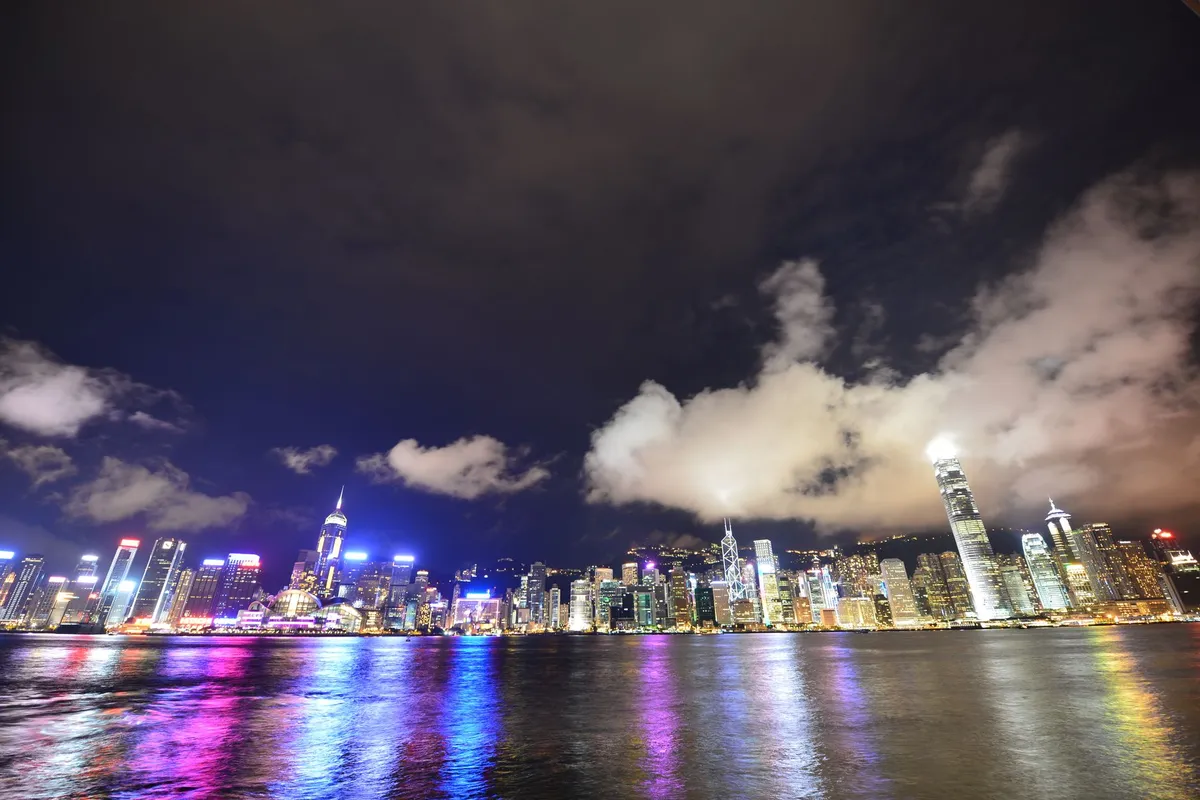 Skyline da ilha de Hong Kong iluminado à noite, visto através de Victoria Harbour, com Bank of China Tower e Two IFC