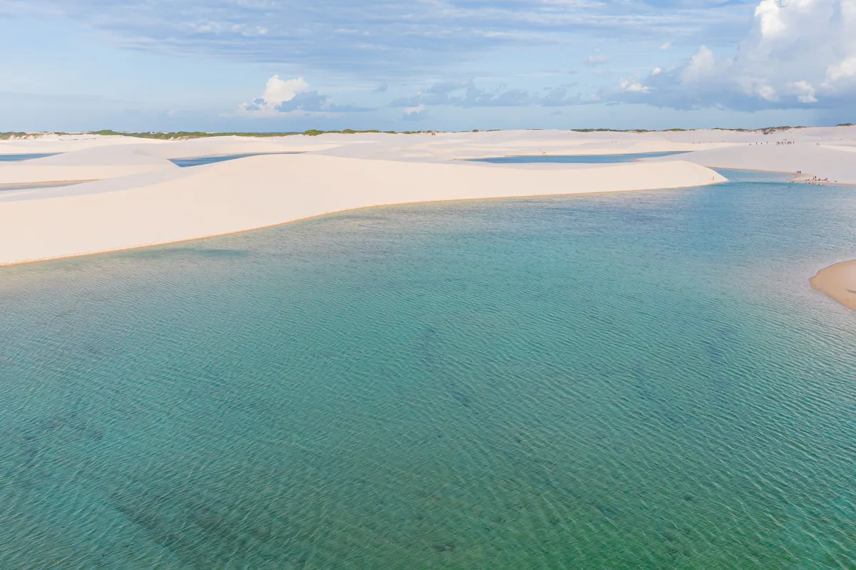 Lagoa de água verde entre dunas brancas nos Lençóis Maranhenses, Maranhão