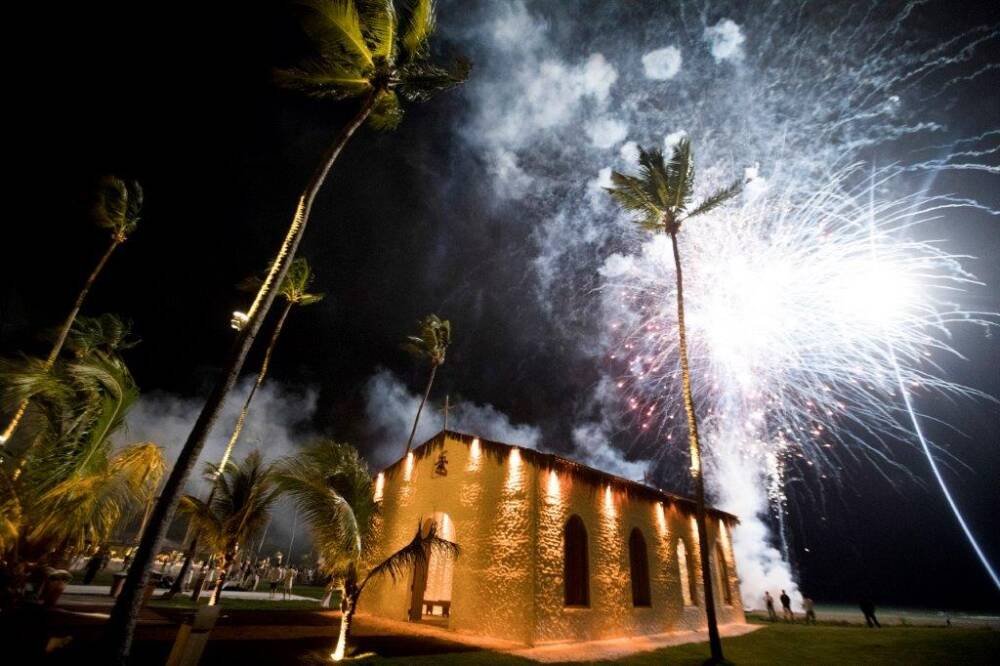Fogos de artifício iluminam a capela e os coqueiros em uma festa de réveillon em São Miguel dos Milagres