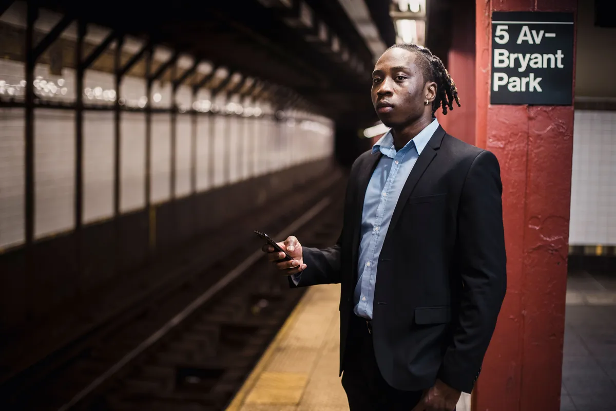 Passageiro com celular na estação 5 Av-Bryant Park em Nova York