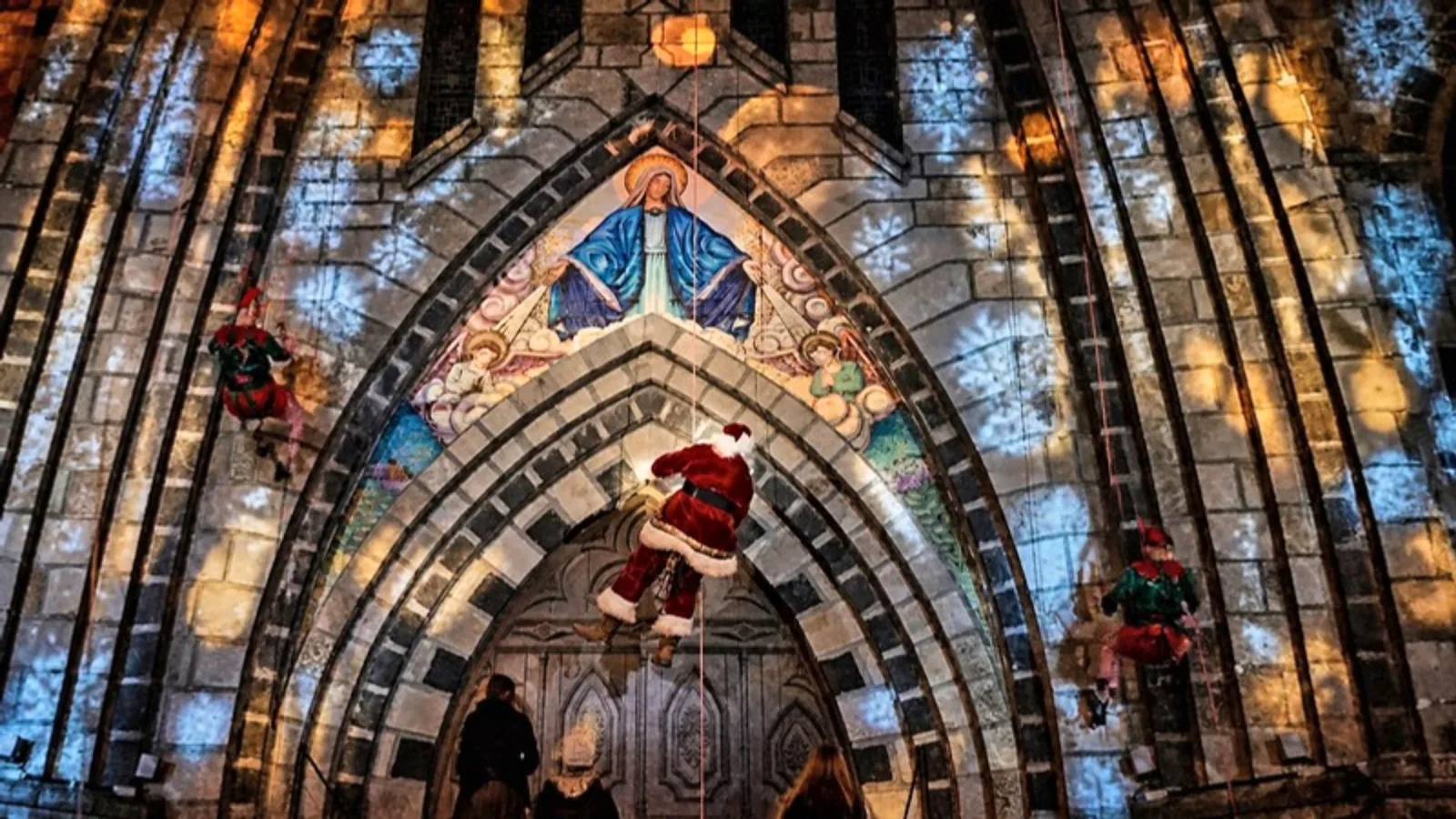 Papai Noel descendo de rapel pela fachada iluminada da Catedral de Pedra, em Canela