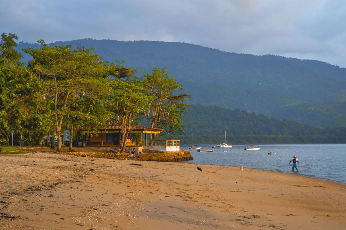 Manhã na praia de Paraty, no litoral sul do Rio de Janeiro, com mar calmo e montanhas ao fundo