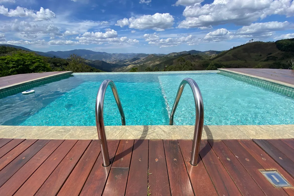 Piscina ao ar livre diante de montanhas, em foto ilustrativa para comparar lazer em hotéis fazenda