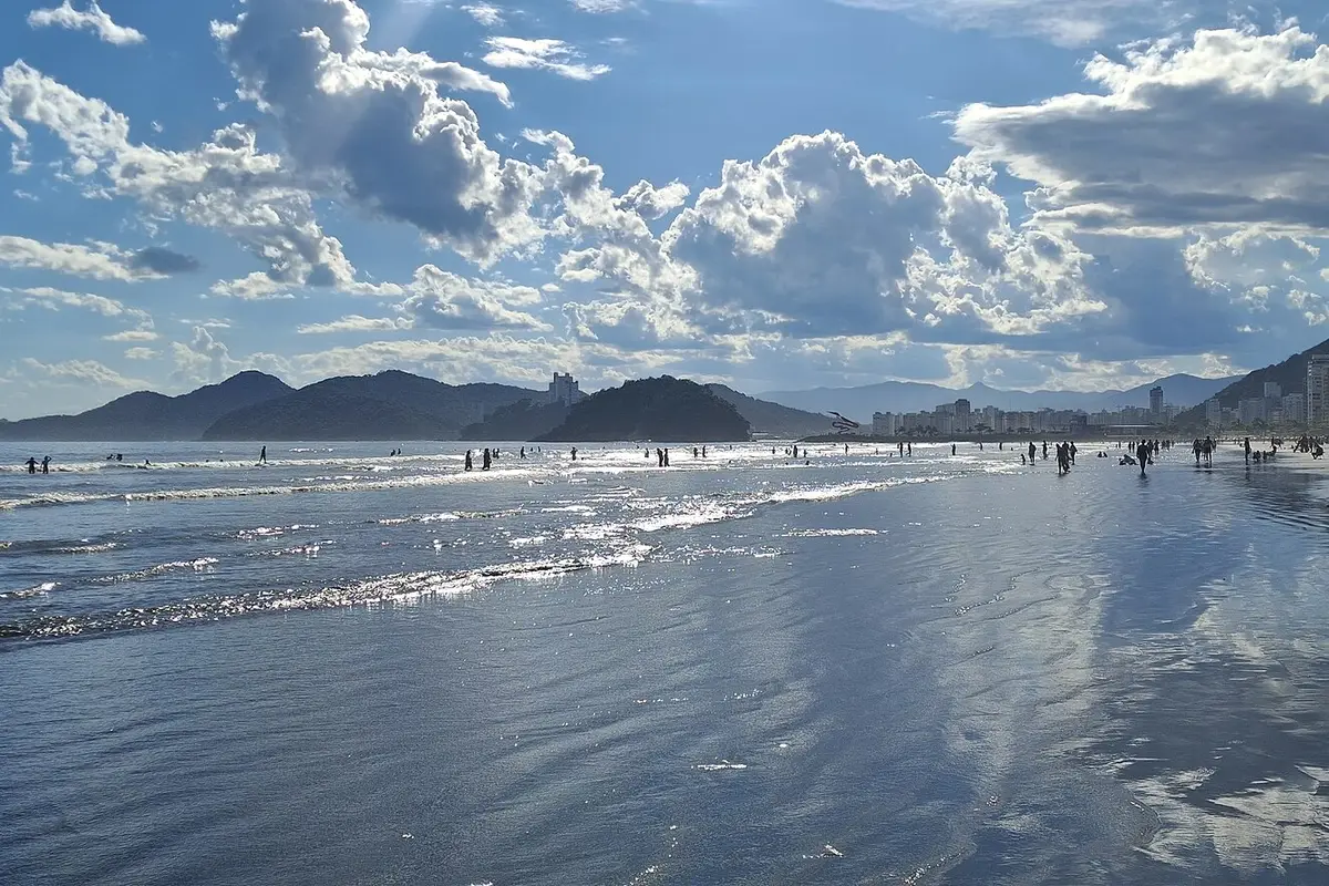 Praia do Gonzaga, em Santos, com a orla de prédios e os morros ao fundo