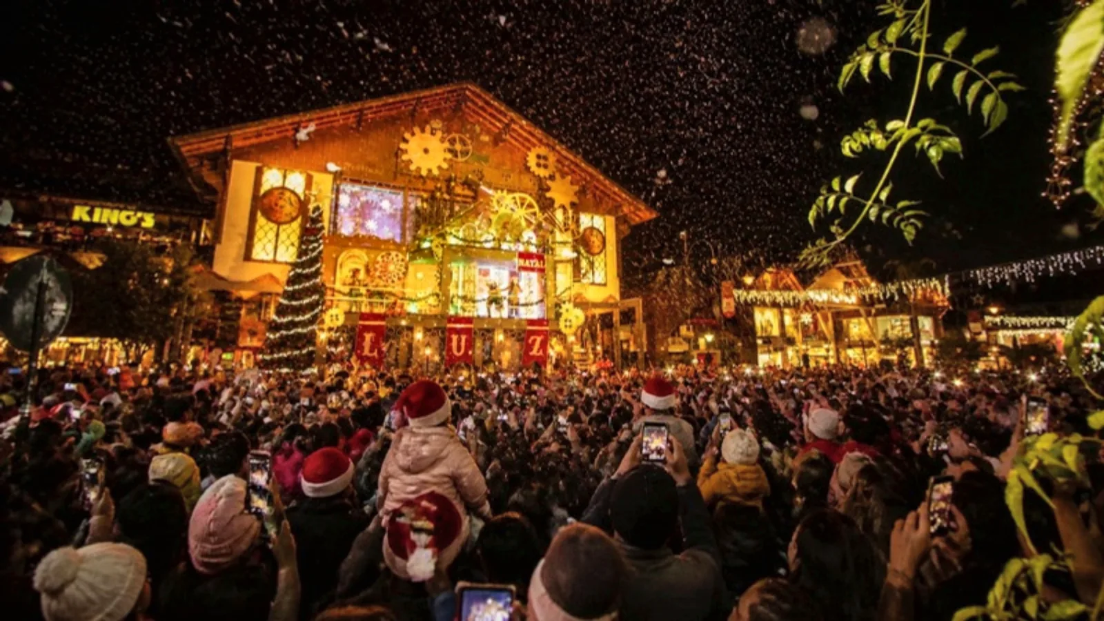 Multidão com celulares erguidos diante do Palácio dos Festivais iluminado no acendimento do Natal Luz, em Gramado