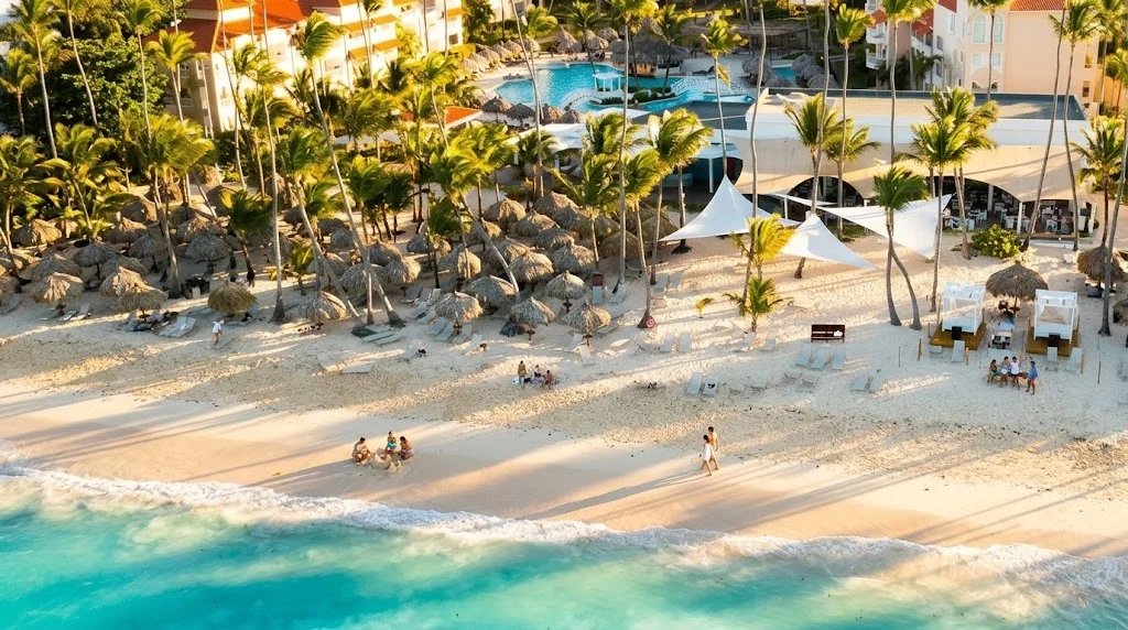 Praia de areia branca com coqueiros e resort em Punta Cana