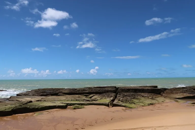 Praia de Caraíva, no sul da Bahia, com rochas e mar verde em dia de sol