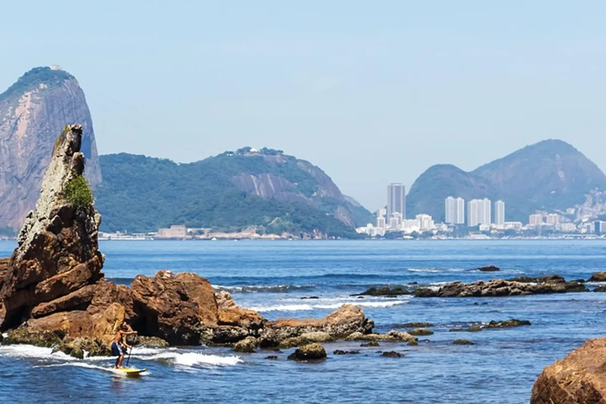 Costão rochoso na orla de Icaraí, em Niterói, com o Pão de Açúcar ao fundo