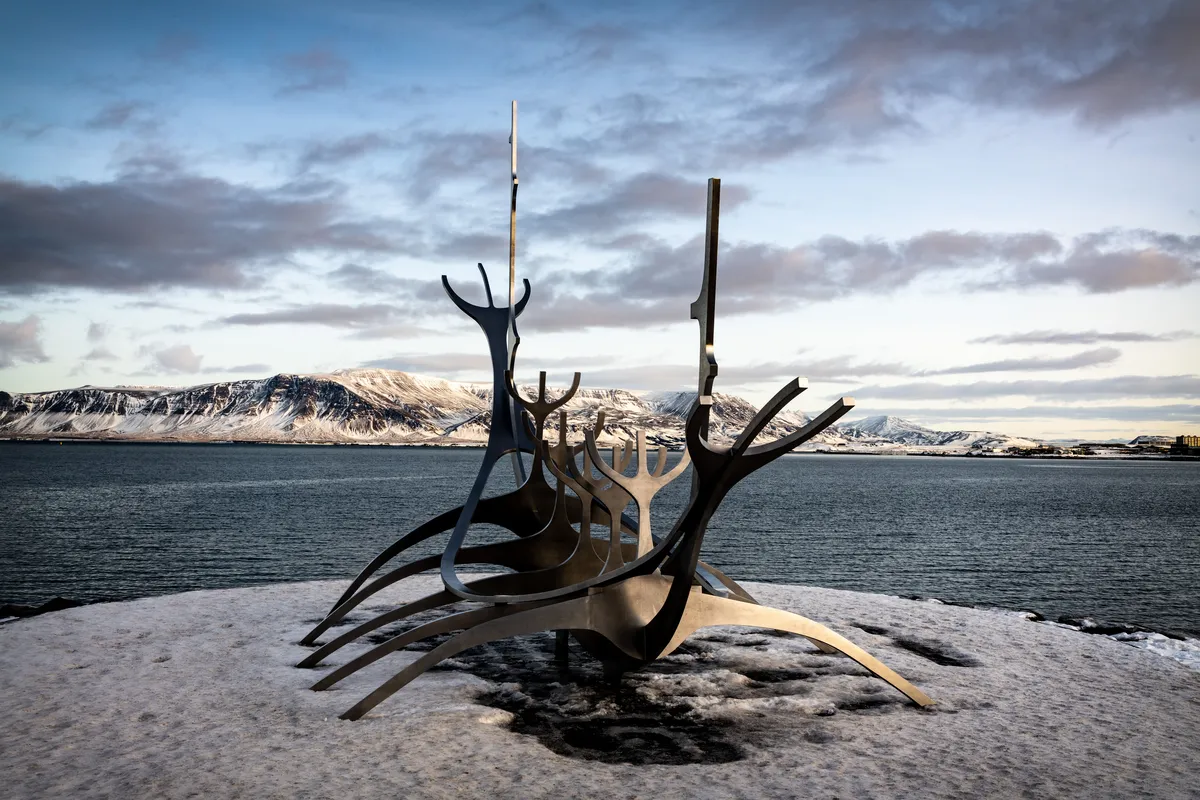Escultura Sun Voyager na orla de Reykjavík com neve e montanhas ao fundo