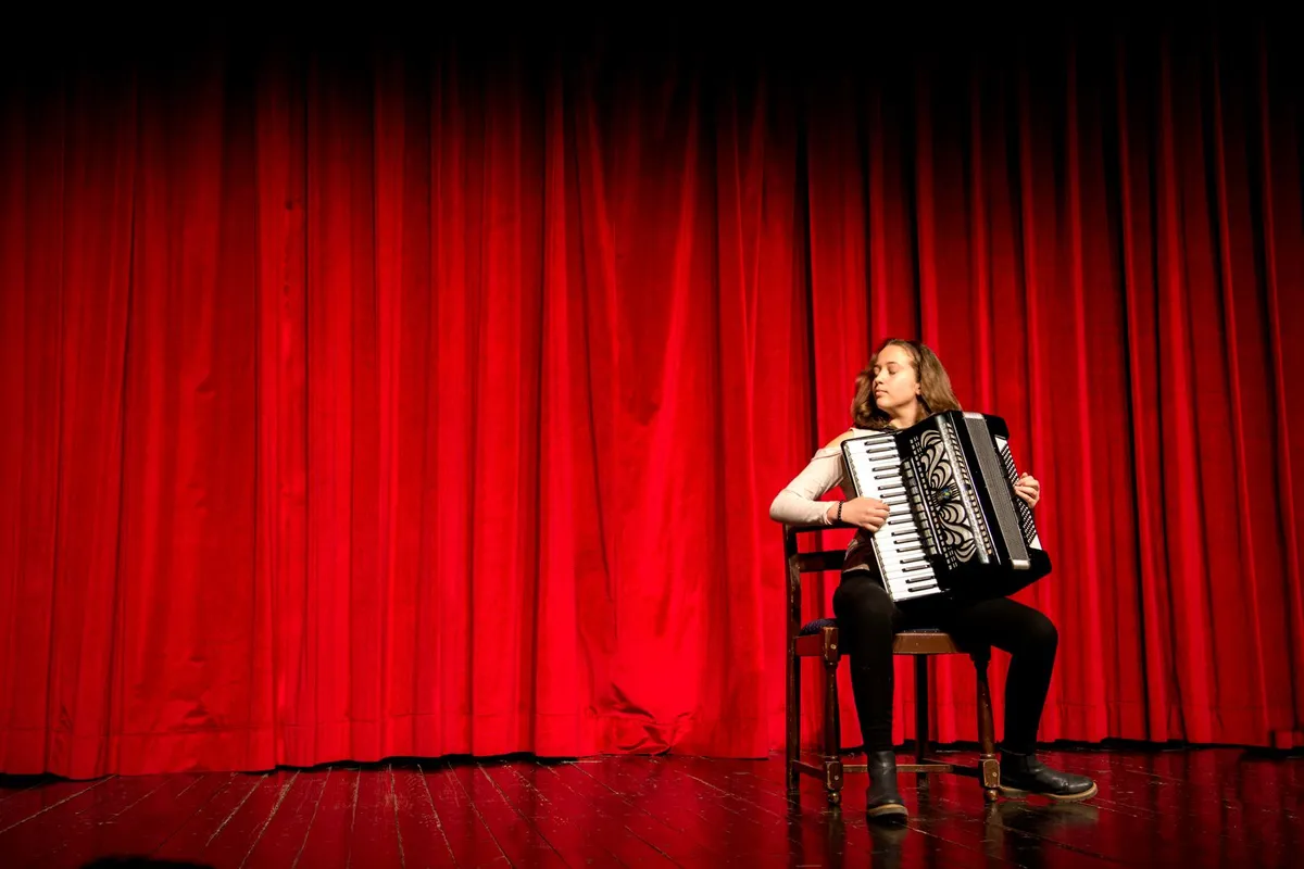 Sanfoneiro tocando em palco iluminado, imagem ilustrativa do clima do Dominguinho em Alto Mar