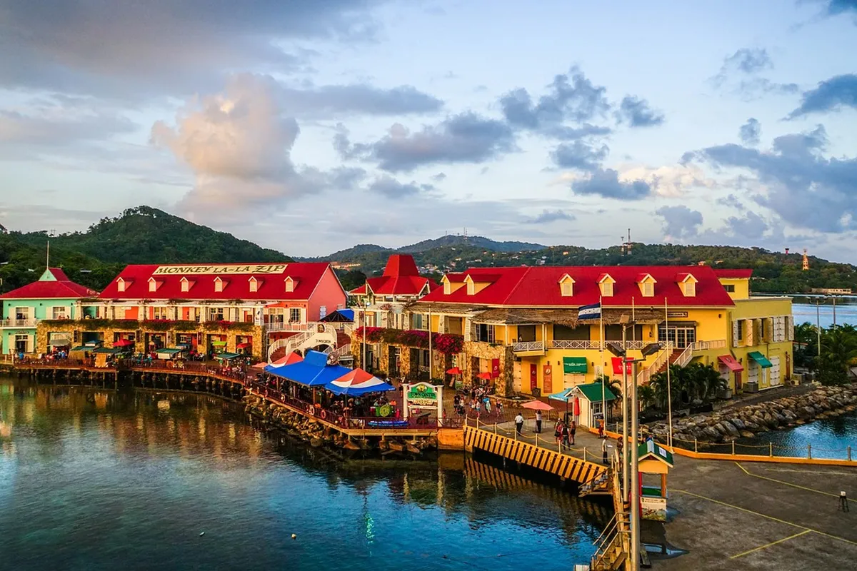 Cais de cruzeiros em Roatán, Honduras, com lojas coloridas à beira d'água ao entardecer