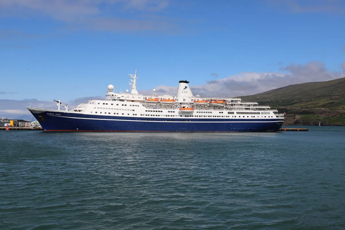 Navio de cruzeiro azul e branco navegando em mar aberto