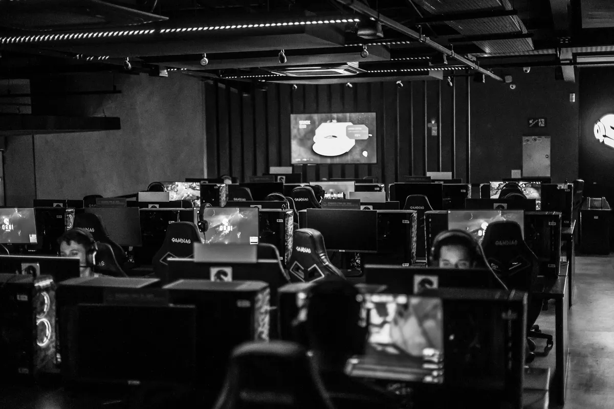 Arena indoor com fileiras de computadores e estações de jogo; imagem ilustrativa.
